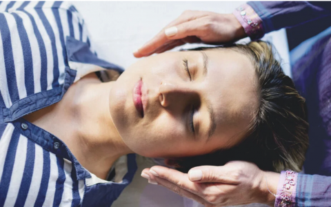 woman laying down with hands cupped near the sides of her head